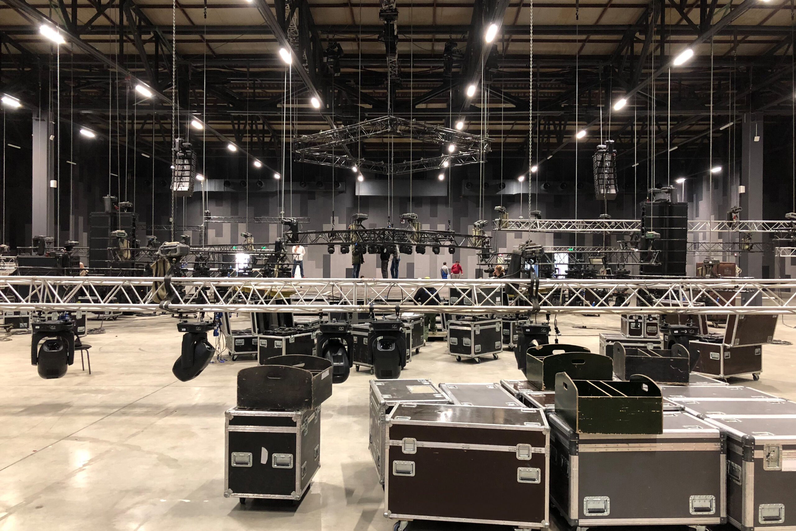 Installation of professional sound, light, video and stage equipment for a concert. Stage lighting equipment is clamped on a truss for lifting. Flight cases with cables.